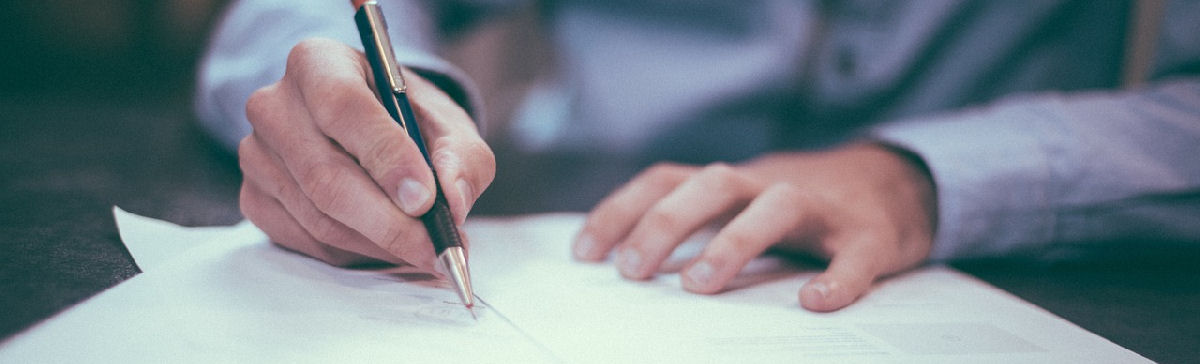 Ihmisen kädet, kynä oikeassa kädessä ja jolla kirjoittaa paperiin