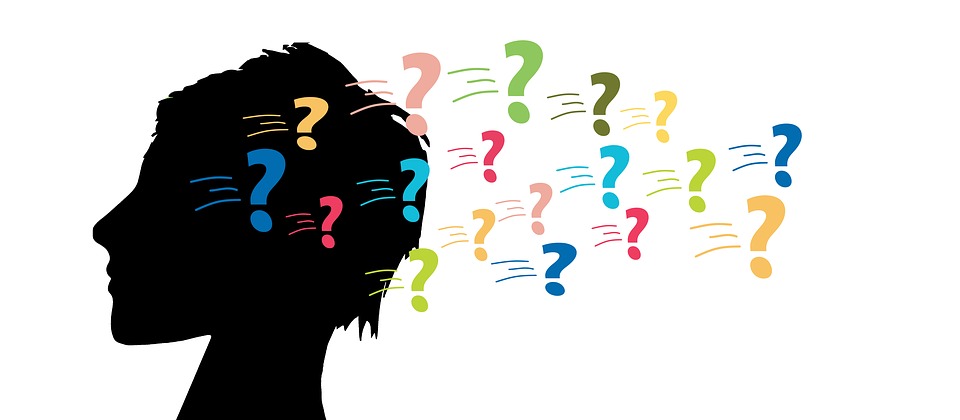 Graafinen kuva pään silhuetista ja erivärisiä kysymysmerkkejä